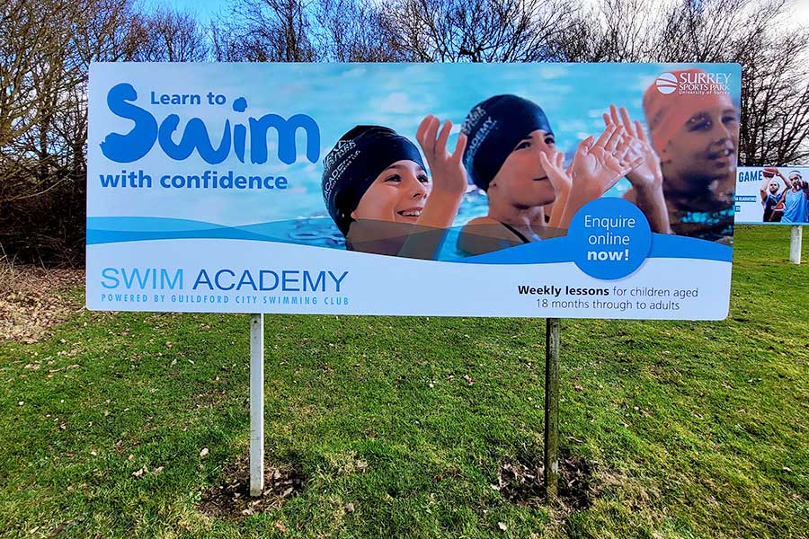 New vinyl printed cover advertising swimming lessons applied to a large aluminium sign outside Surrey Sports Park by Bluedot Display