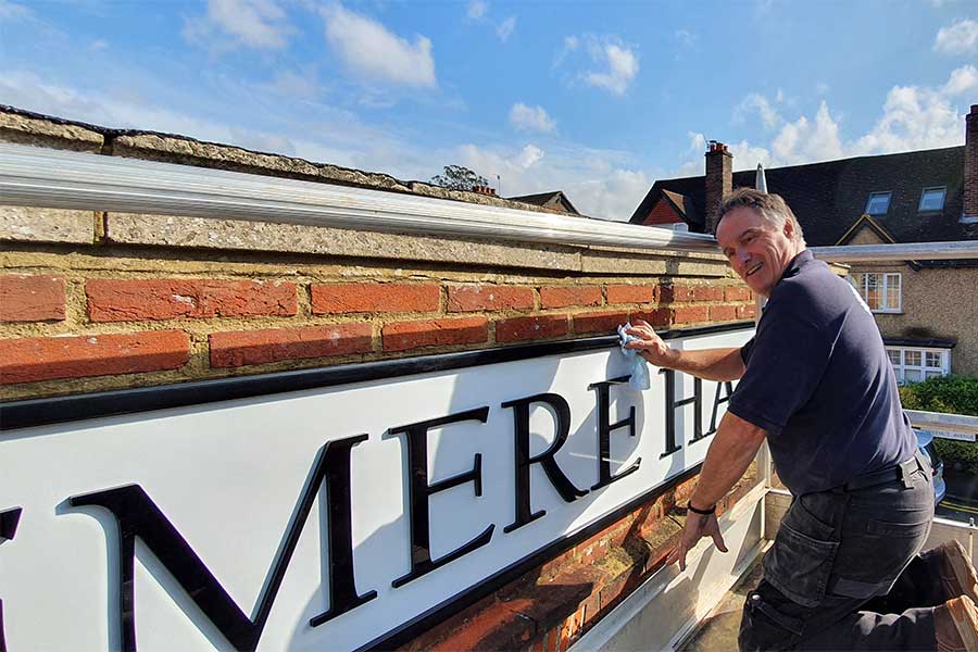 John from Bluedot Display installing a new metal fascia sign at Haslemere Hall in Haslemere